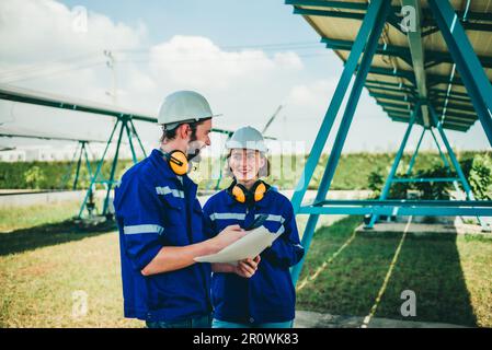 Solaringenieure untersuchen Schaltschrankarrays auf Bauernhöfen anhand von Bauplänen und Zeichnungen visuell, um sicherzustellen, dass Ausrichtung, Oberfläche, Sonnenlicht und zugänglich sind Stockfoto