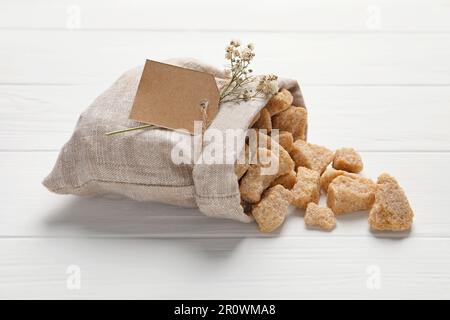 Beutel mit braunen Zuckerstücken auf einem weißen Holztisch Stockfoto