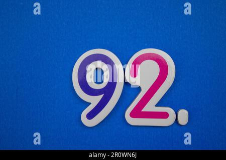 Die Nummer 92, auf blauem Hintergrund, von oben fotografiert, blau und rosa. Stockfoto