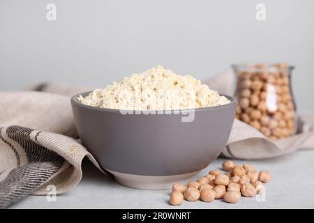 Kichererbsenmehl in Schüssel und Samen auf hellgrauem Tisch Stockfoto