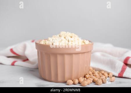 Kichererbsenmehl in Schüssel und Samen auf weißem Marmortisch Stockfoto