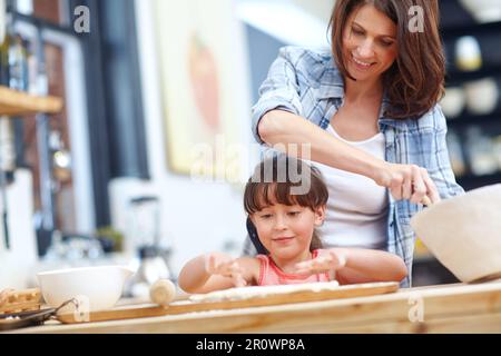 Backen ist Liebe, die sichtbar gemacht wird. Eine Mutter und Tochter, die zusammen backen. Stockfoto
