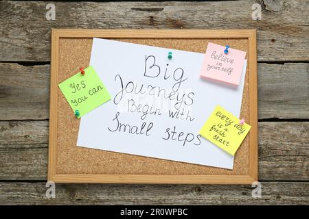 Korkbrett mit motivierenden Zitaten auf Holztisch, Draufsicht Stockfoto