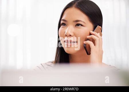 Multitasking wie ein Profi. Eine junge Geschäftsfrau, die telefoniert, während sie an ihrem Schreibtisch sitzt. Stockfoto