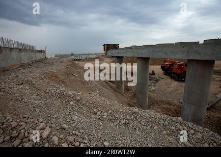 Südkasachstan - April 26 2012: Entwicklung der Autobahn Westeuropa-Westchina. Bau einer Brücke an der Straßenkreuzung. Blick auf graue Sturmwolke BA Stockfoto