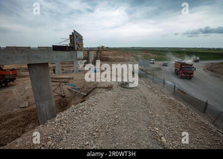 Südkasachstan - April 26 2012: Entwicklung der Autobahn Westeuropa-Westchina. Bau von Straßenkreuzung und Brückenelementen auf grauem Sturm Cl Stockfoto