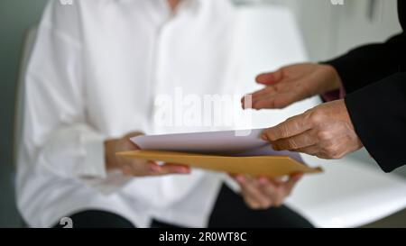 Nahaufnahme einer professionellen Geschäftsfrau oder eines HR-Managers, die/der vor einem Bewerbungsgespräch die Dokumente des Bewerbers überprüft. Stockfoto