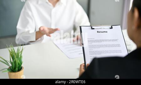 Nahaufnahme eines professionellen Recruiters oder HR-Managers, der während eines Bewerbungsgesprächs den Lebenslauf eines Bewerbers liest. Stellenvermittlung, Vorstellungsgespräch, Karriere. Stockfoto