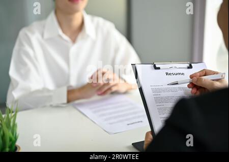 Nahaufnahme eines professionellen Recruiters oder HR-Managers, der während eines Bewerbungsgesprächs den Lebenslauf eines Bewerbers liest. Stockfoto