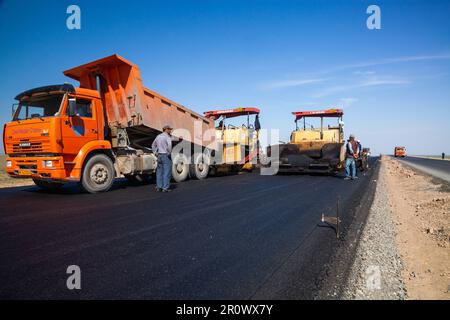 Provinz Kyzylorda, Kasachstan, 29. April 2012: Bau der Autobahn Westeuropa-Westchina. Kipplaster entlädt heißen Asphalt. Stockfoto