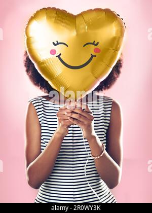 Liebe, Lächeln und eine Frau mit einem Herzballon, isoliert auf pinkfarbenem Hintergrund in einem Studio. Glücklich, süß und ein Mädchen mit einem Geschenk oder Geschenk für Stockfoto