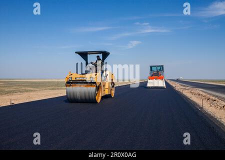 Provinz Kyzylorda, Kasachstan, 29. April 2012: Bau der Autobahn Westeuropa-Westchina. Asphaltverdichter von Caterpillar und Hamm flachen asphal ab Stockfoto