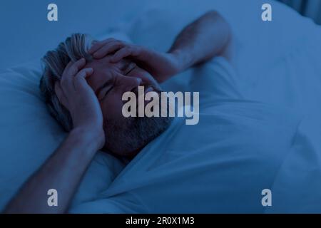 Draufsicht auf einen unglücklichen Mann mit nächtlichen Kopfschmerzen Stockfoto
