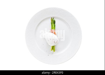 Pochiertes Ei auf Spargel in Speck. Isoliert auf weißem Hintergrund Stockfoto