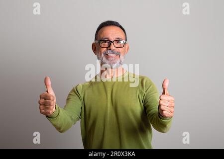 Ein glücklicher weißer Senior-Mann mit Brille zeigt Daumen hoch, empfiehlt und gibt Ratschläge und Angebote Stockfoto