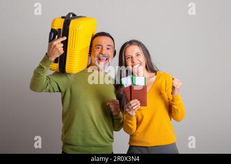 Glücklicher, aufgeregter weißer älterer Ehemann mit Koffer und Frau mit Tickets, Pässe, die Siegesgeste machen Stockfoto