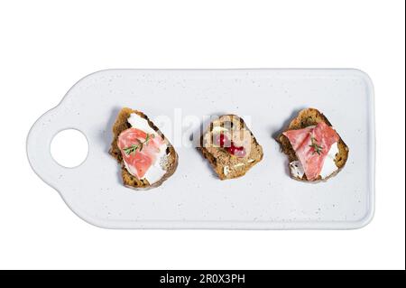 Toast mit Parma, Salami und Gänsepastete auf einem weißen Schneidebrett isoliert auf weißem Hintergrund Stockfoto