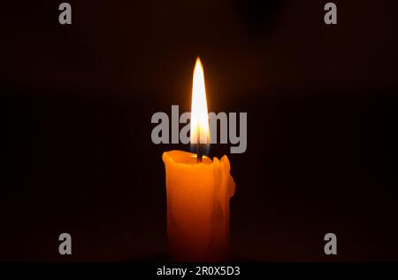 Leuchtende brennende Kerze in der Dunkelheit. Gedenkfeier und Symbol des Gedenkfeiertags. Stockfoto