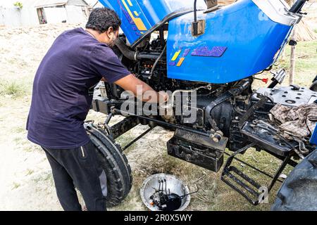 Ein Mechaniker mittleren Alters repariert einen Traktormotor oder eine Ölpumpe, die in der Landwirtschaft verwendet wird. Stockfoto