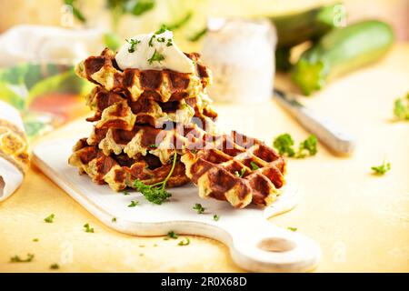 Hausgemachte kohlenhydratarme Zucchini-Waffeln auf weißem Holzbrett auf gelbem Hintergrund. Konzept der Keto-Diät. Stockfoto