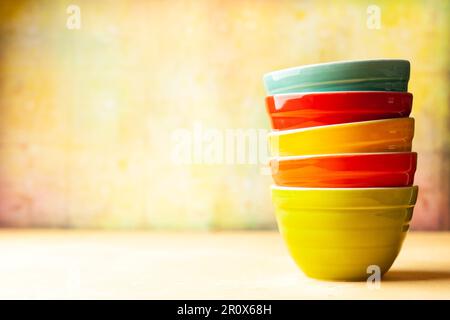 Hintergrund für Küchenutensilien mit mehrfarbigen Keramikschüsseln auf gelbem Hintergrund. Konzept der Einrichtung in der Küche. Vorderansicht, Kopierbereich. Stockfoto