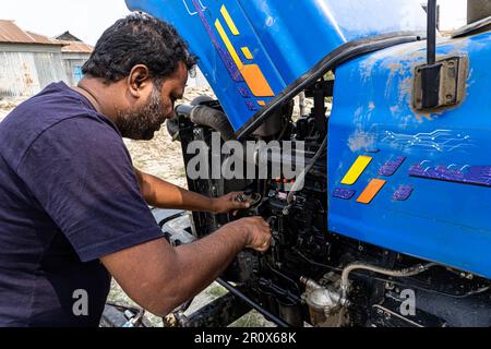 Maschinenwartung, Mechaniker, der die Ölpumpe des Traktors repariert und den Ölstand im Freien prüft Stockfoto