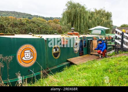 Ein Walker, der einen Kaffee im Café on the Barge am Kennet und Avon-Kanal, Bathampton Village, in der Nähe von Bath, Somerset, England, kauft Stockfoto