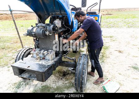 Nahaufnahme der Hydraulikleitungen der Schwerindustrie. Öffnen Sie die Motorhaube des Traktors. Landmaschinenmechaniker arbeitet an blauem Traktor Stockfoto