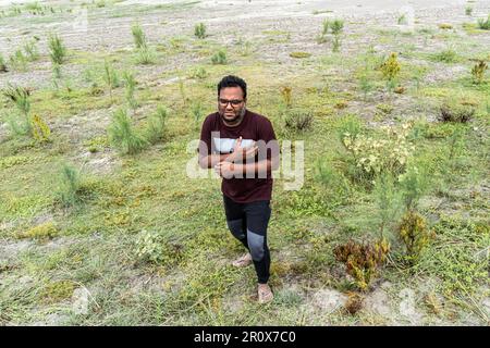 Ein Mann mit Brustschmerzen, der an einem Herzinfarkt auf einem Feld leidet. Gesundheitskonzept. Nahaufnahme eines asiatischen Bangladesch-Mannes mit Hand auf der Brust Stockfoto