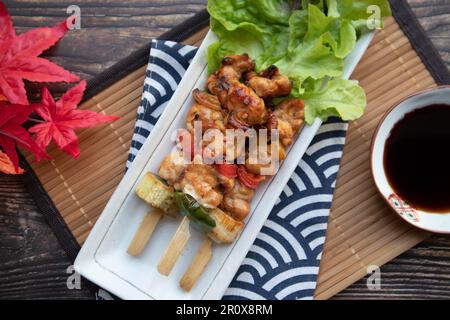 Yakitori: Japanischer Hähnchenspieß und gedünstete Eier lagen auf einem Holztisch mit Blick von oben Stockfoto