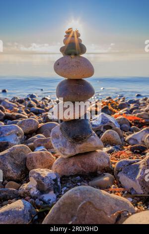 Ein malerischer Blick auf einen Kieselturm an einem felsigen Strand bei Sonnenuntergang Stockfoto
