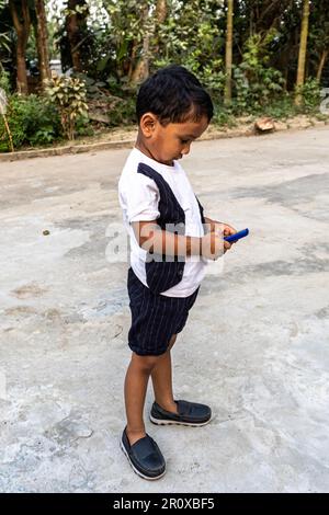 Porträtansicht eines Jungen mit Handy. Ein kleiner Junge benutzt ein Handy, um positive Emotionen zu massieren. Ein kleiner Junge am Telefon Stockfoto