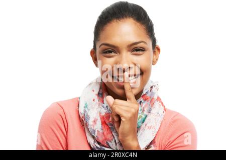 Ihr Geheimnis mit einem Lächeln bewahren. Eine wunderschöne junge Frau, die lächelt, während sie ihren Finger an ihre Lippen hält. Stockfoto