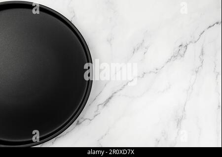 Draufsicht auf schwarzes Schild auf weißem Marmorhintergrund. Lebensmittelpräsentation flach liegend. Speicherplatz kopieren. Stockfoto