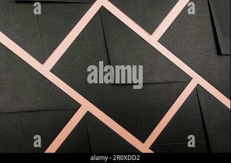 Draufsicht der schwarzen Umschläge auf pinkfarbenem Hintergrund. Flaches Ablegen, Kopierbereich. Stockfoto
