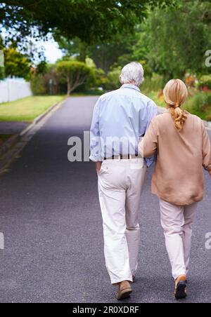Sie stecken zusammen drin. Rückblick eines älteren Paares, das spazieren geht. Stockfoto