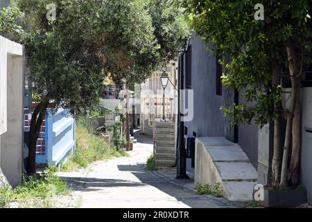 Steingepflasterter Fußweg in Ani Poli, der historischen oberen Altstadt von Thessaloniki, Griechenland, führt an einem sonnigen Tag hinunter in die Innenstadt. Stockfoto