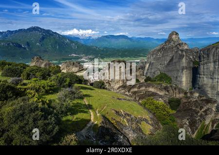 Blick von den Meteora Felsen über das Dorf Kalambaka im Tal bis zu den Bergen und schneebedeckten Gipfeln, Landschaft im Zentrum Griechenlands, wolkiges Blau Stockfoto