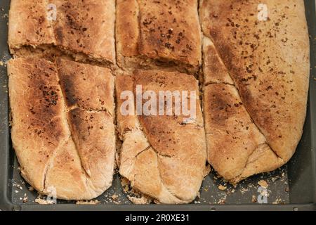 Frisch gebackenes Brot aus Weizen und Vollmehl mit Hefe auf einem Backblech, Blick auf Engel von oben, ausgewählter Fokus, schmale Feldtiefe Stockfoto