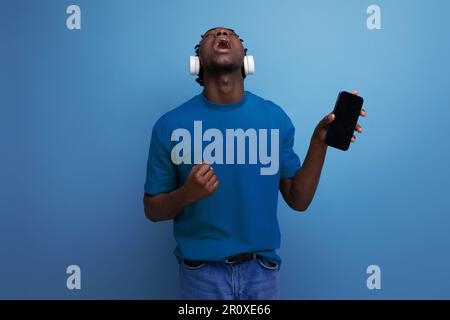 Energiegeladener junger Mann mit Kopfhörern und Mobiltelefon Stockfoto