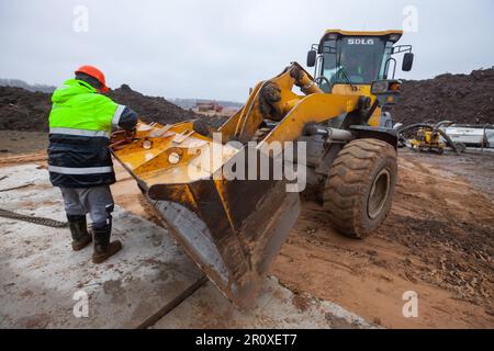 USt-Luga, Oblast Leningrad, Russland - 16. November 2021: Arbeiter und SDLG-Bulldozer Stockfoto