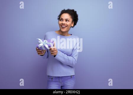 Junge brünette Frau mit Afrohaar bekam ein Geburtstagsgeschenk Stockfoto