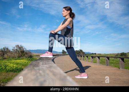 Läuferin, die draußen Beinübungen macht Stockfoto