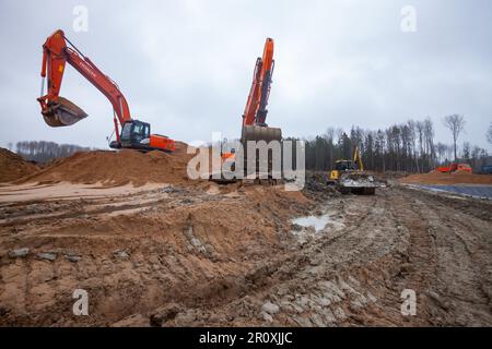 USt-Luga, Oblast Leningrad, Russland - 16. November 2021: Bodenarbeiten an Regentagen. Nasse Schlammstraße und Wasser. Stockfoto