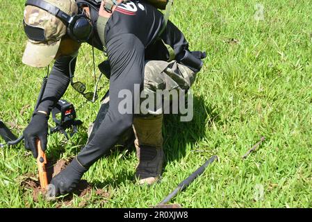 Stadt: Marilia, Sao Paulo, Brasilien, 25. März 2023: Mann, der Zeiger in der Detektorkampagne mit Metalldetektor auf einem Grasfeld verwendet. Hobbywettbewerb Stockfoto