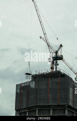 Gebäudekrane werden in der Konstruktion eingesetzt, um Materialien in die Höhe zu heben. Stockfoto