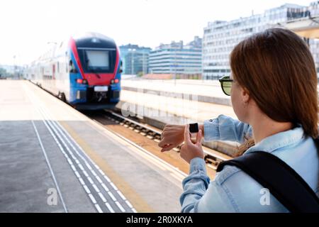 Der Passagier hat den Zug verpasst. Eine Frau steht auf dem Bahnsteig und überprüft die Zeit auf ihrer Armbanduhr. Stockfoto