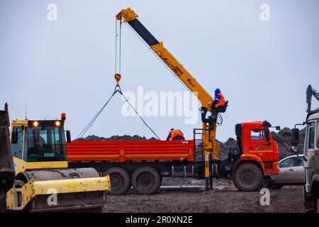 USt-Luga, Oblast Leningrad, Russland - 16. November 2021: Arbeiter entladen Betonplatten vom Lkw Stockfoto
