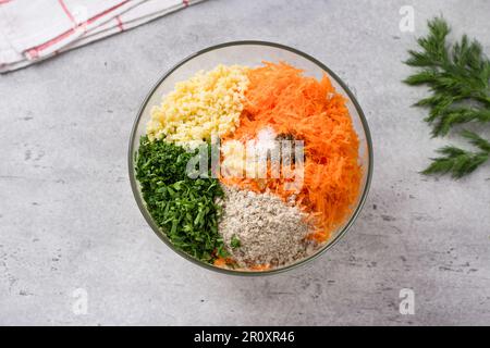 Glasschale mit Zutaten für vegane Schnitzel, Burger: Hirse, Karotten, Samen, Kräuter, Knoblauch und Gewürze mit einem Haufen frischen Dill, Draufsicht. Stadium o Stockfoto