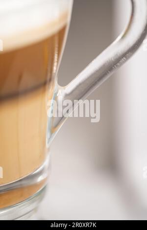 Eine Glastasse Latte Kaffee mit Milchschaum. Selektiver Fokus. Isoliert auf weißem Hintergrund. Stockfoto